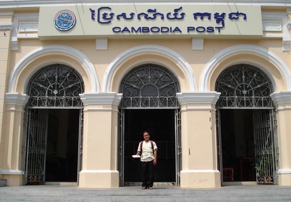 A photo of a man standing outside a Cambodian Post Office