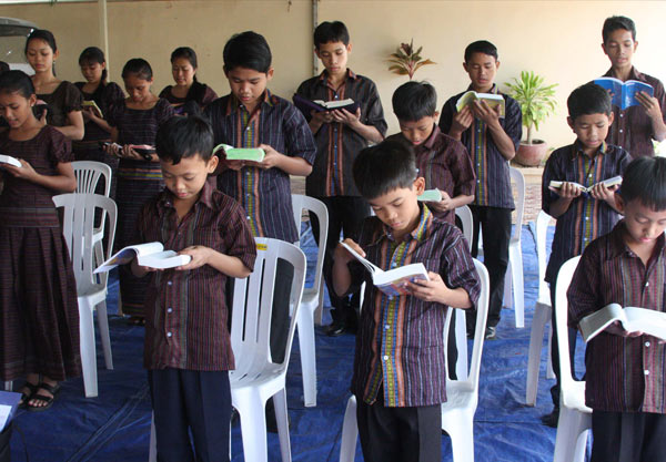 A photo of a group of children reading the bible at the Cambodian Christian Arts Ministry